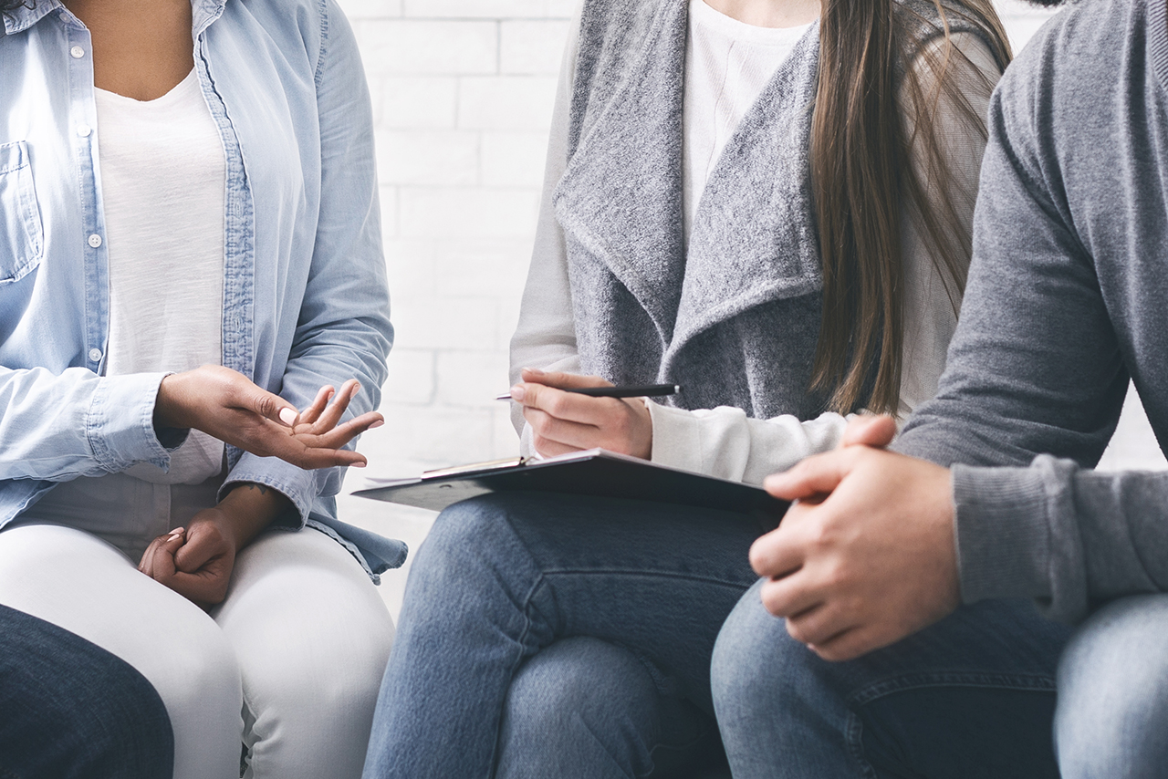 Counselor with clipboard talking to patients at office Support group therapy. Counselor with clipboard talking to patients at office, panorama